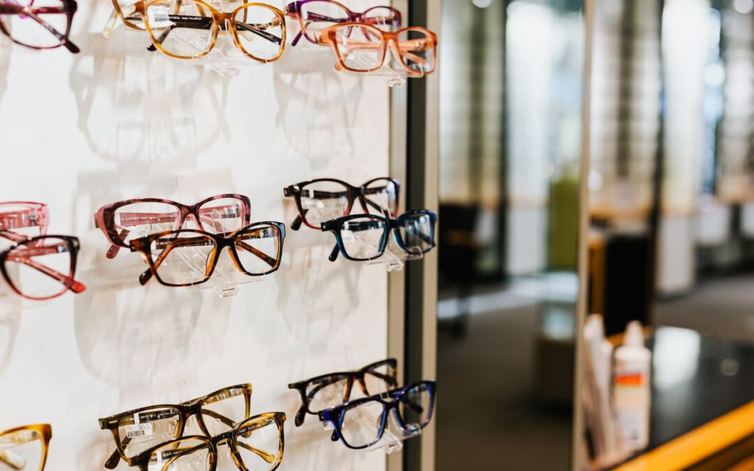 Une grande variété de montures de lunettes de vue aux formes et couleurs diverses exposées sur le présentoir d'un magasin d'optique.